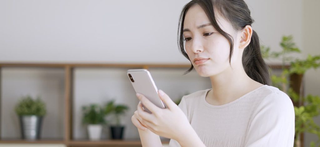 スマホを持って悩む女性